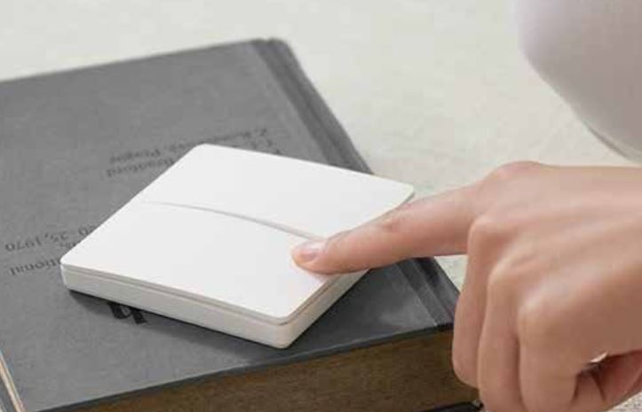 A Dimi keypad placed on top of a book that being pressed - Wireless Control Battery Free